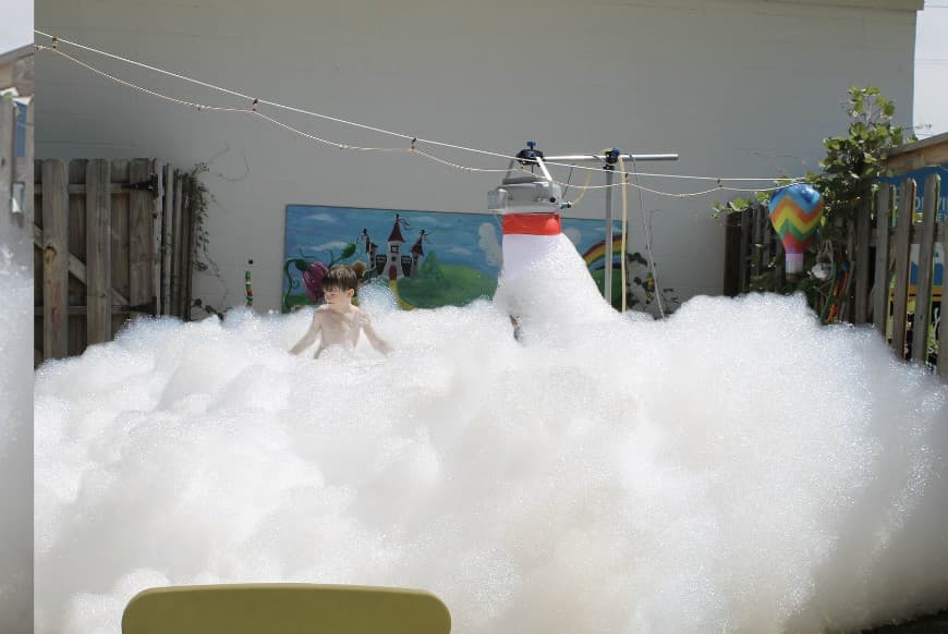 Kid playing in foam beside the foam machine